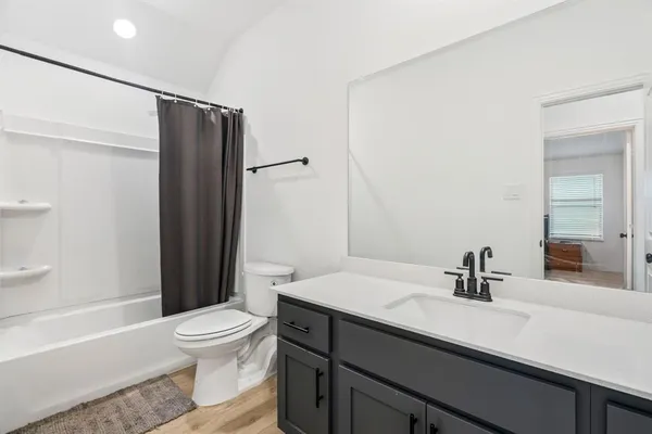 a bathroom with a sink a toilet a mirror and shower