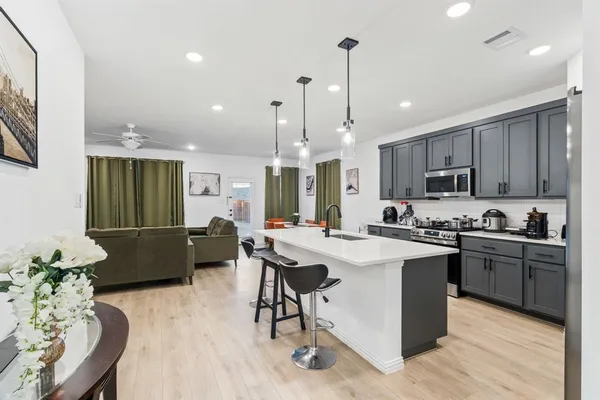 a kitchen with stainless steel appliances kitchen island granite countertop a sink a stove a dining table and chairs