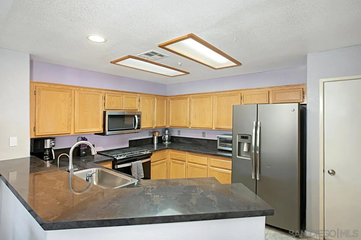 405 Whispering Willow Drive, Unit B Santee, CA 92071 - Photo 7 of 29 a kitchen with stainless steel appliances granite countertop a sink a stove and a refrigerator
