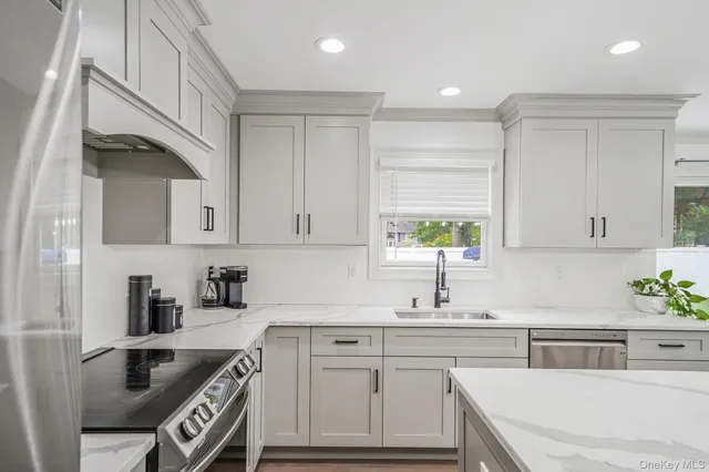 a kitchen with a sink dishwasher and white cabinets with wooden floor