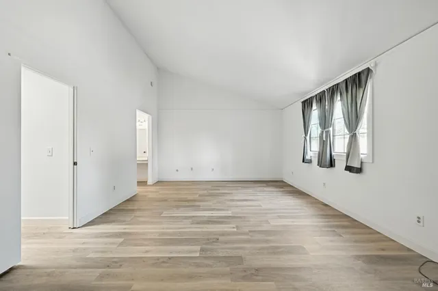 a view of an empty room with wooden floor and windows