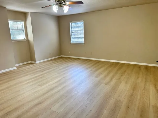 a view of an empty room with window and wooden floor