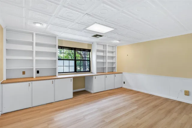 a large white kitchen with wooden floor and cabinets