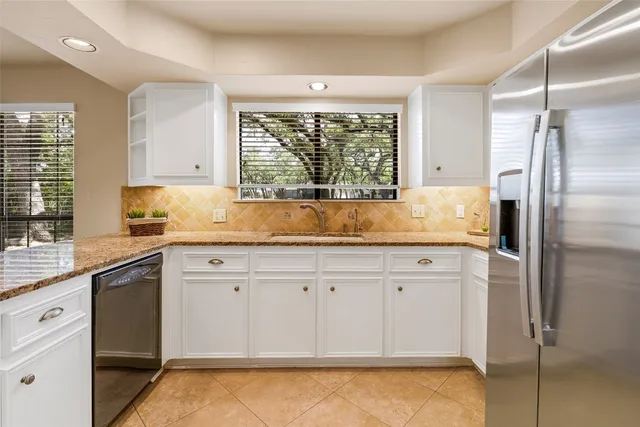 a kitchen with granite countertop a sink stainless steel appliances and cabinets