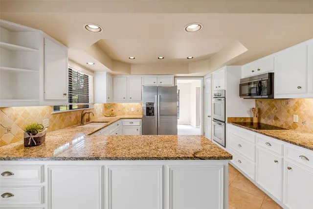 a kitchen with granite countertop a sink a counter top space stainless steel appliances and cabinets