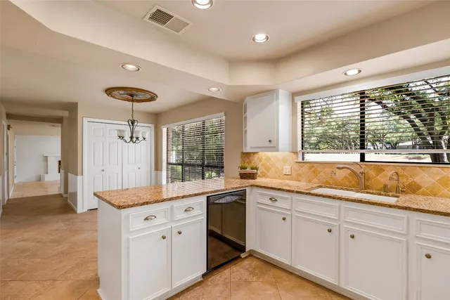 a open kitchen with granite countertop a sink and white cabinets with wooden floor