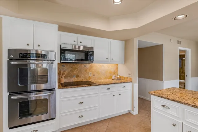 a kitchen with granite countertop white cabinets and stainless steel appliances
