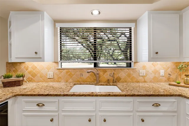a bathroom with a granite countertop sink and a window