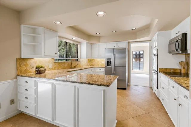 a kitchen with granite countertop a sink a counter top space stainless steel appliances and cabinets