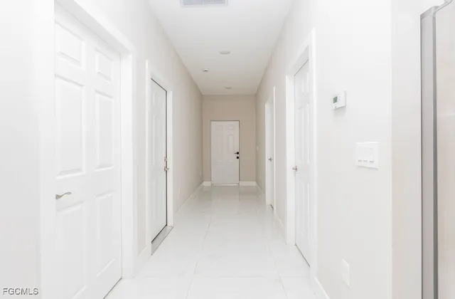 a large white kitchen with kitchen island a sink a stove a refrigerator and a dining table with wooden floor