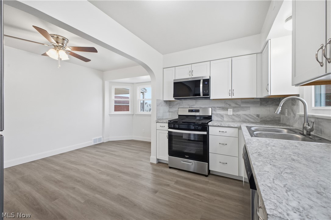 227 Wilson Street Struthers, OH 44471 - Photo 13 of 44 Kitchen with stainless steel appliances, white cabinetry, light countertops, arched walkways, and tasteful backsplash