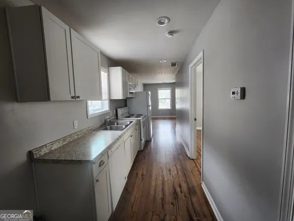 a kitchen with granite countertop a sink stove and refrigerator