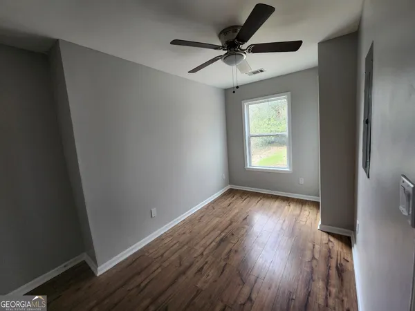 a view of an empty room with wooden floor and a window