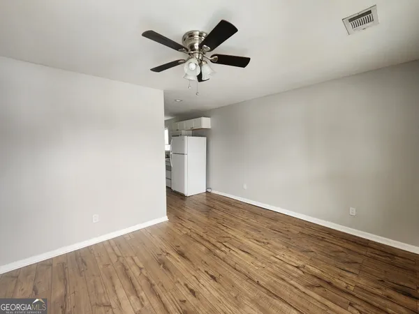 an empty room with wooden floor and a ceiling fan