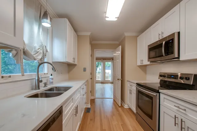 a kitchen with stainless steel appliances granite countertop a sink a stove top oven and wooden floors