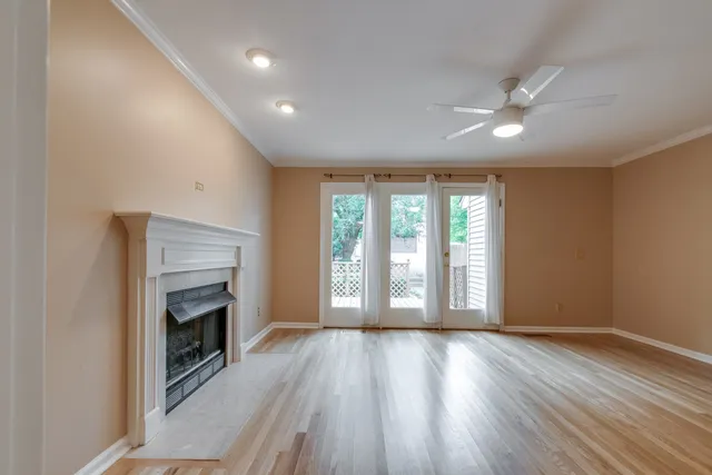 an empty room with wooden floor fireplace and windows