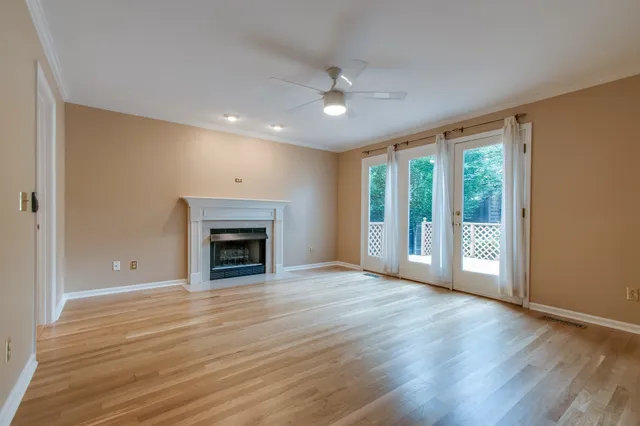 a view of an empty room with wooden floor fireplace and a window
