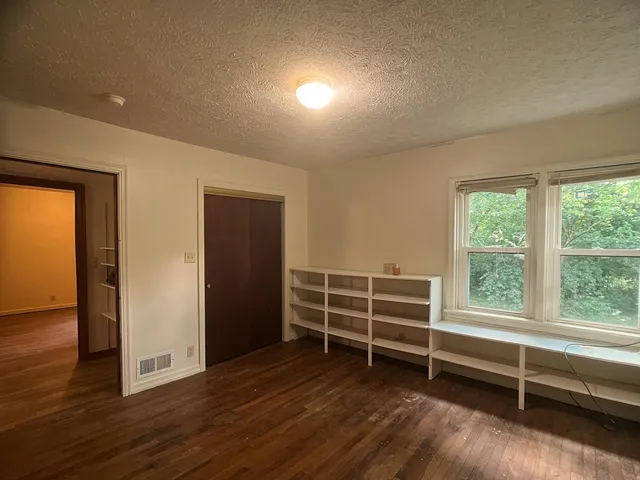 an empty room with wooden floor and windows