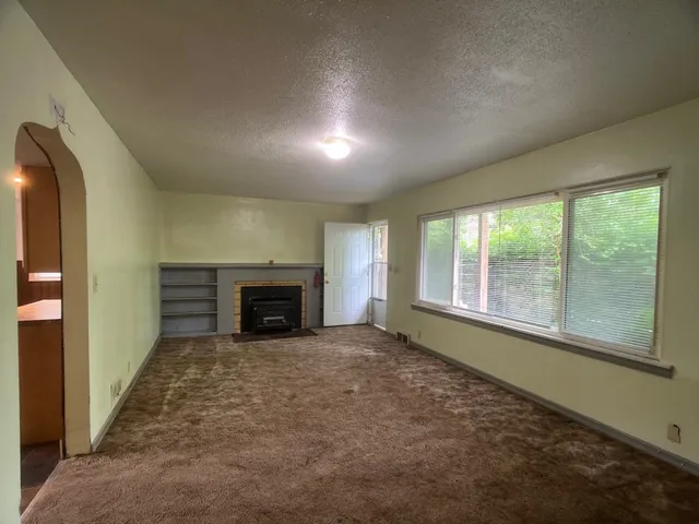 an empty room with windows and fireplace
