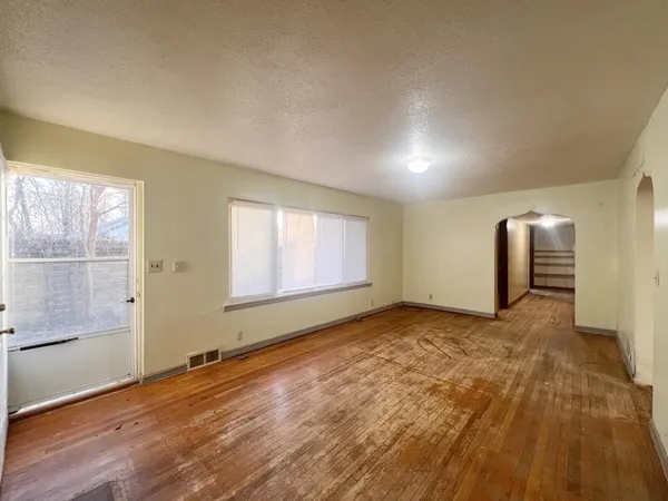 an empty room with wooden floor and windows