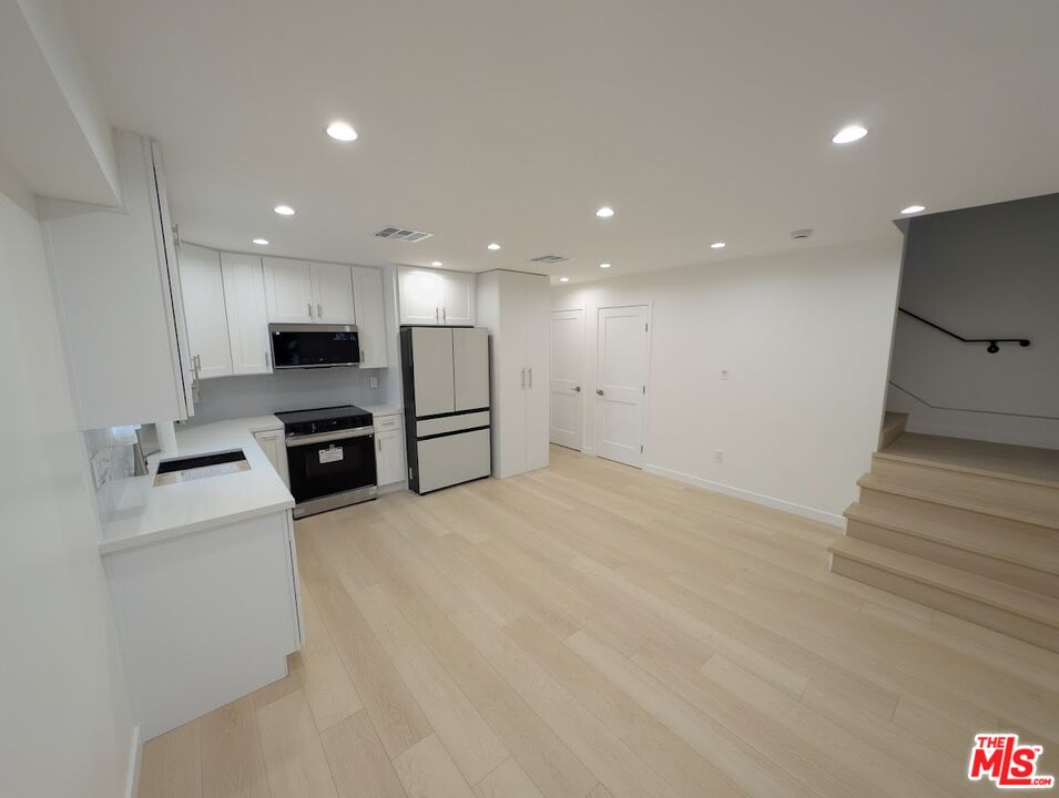 10623 Stanwin Avenue Mission Hills, CA 91345 - Photo 4 of 18 a view of kitchen with refrigerator stove microwave and wooden floor