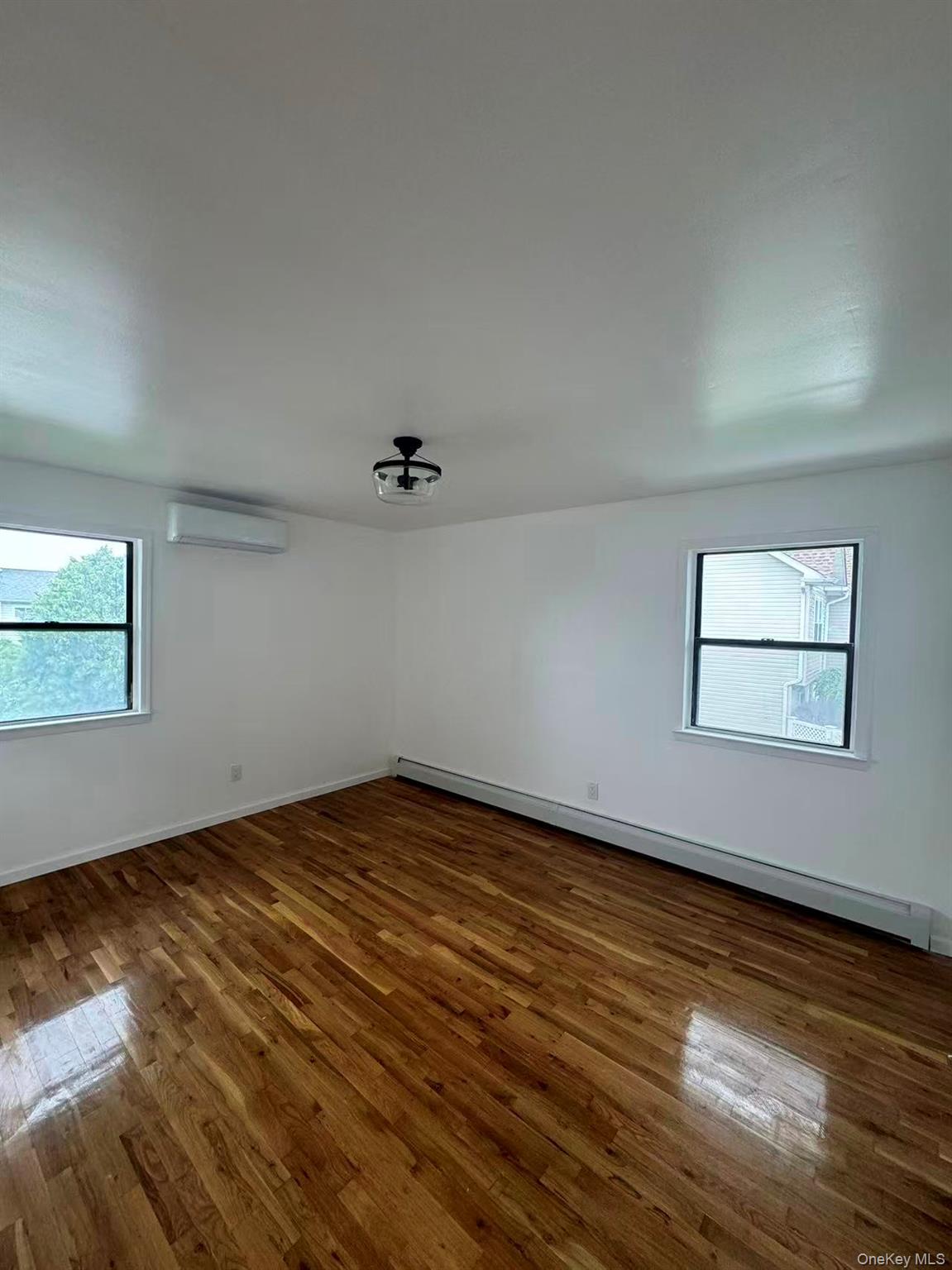 376 Newbridge Road East Meadow, NY 11554 - Photo 4 of 7 an empty room with wooden floor and windows