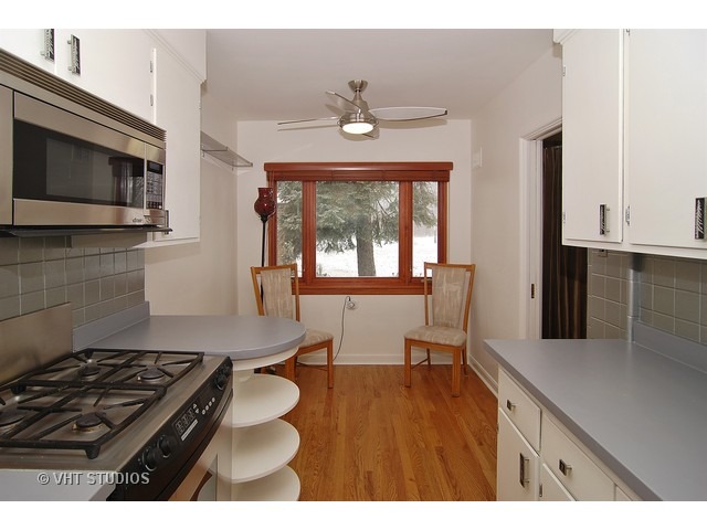 229 Blackhawk Road Riverside, IL 60546 - Photo 3 of 25 a kitchen with stainless steel appliances a stove a microwave a sink and white cabinets