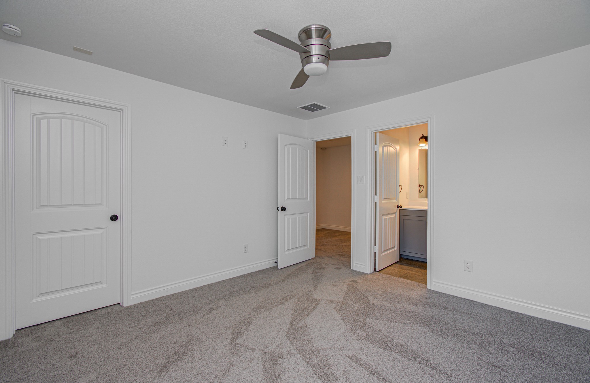 6621 North Main Street Houston, TX 77009 - Photo 28 of 41 Located on the third floor this secondary bedroom features fresh carpet, a modern ceiling fan, and neutral walls, creating a bright and airy space. It includes two doors leading to a closet and an adjoining bathroom with contemporary fixtures.