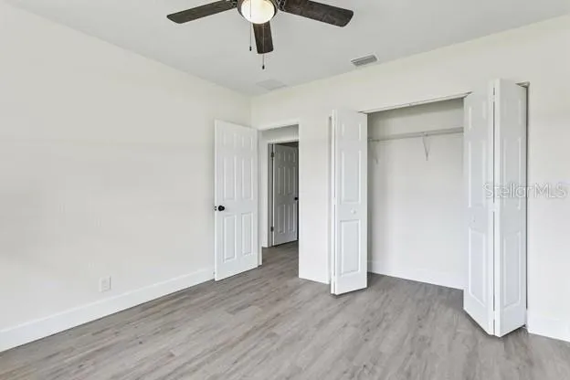 an empty room with wooden floor and ceiling fan
