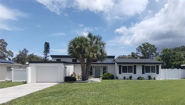 a front view of a house with a garden and trees