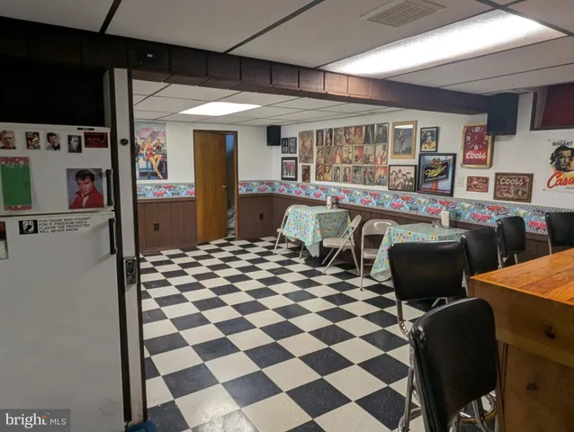a living room with a black white checkered floor with couches and flat screen tv