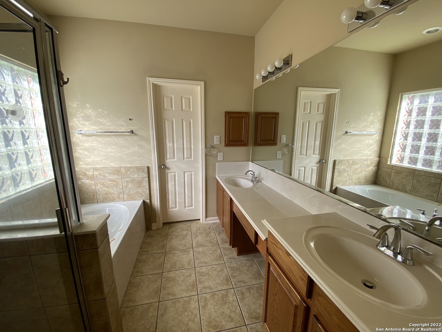 15518 Portales Pass Helotes, TX 78023 - Photo 14 of 25 a bathroom with a double vanity sink a mirror and a bathtub
