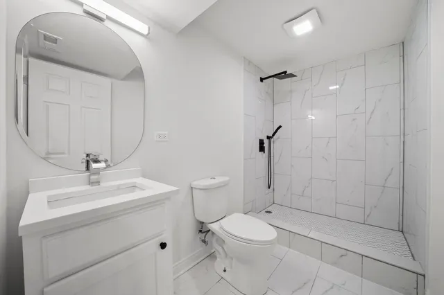 a bathroom with a toilet a sink a mirror and shower
