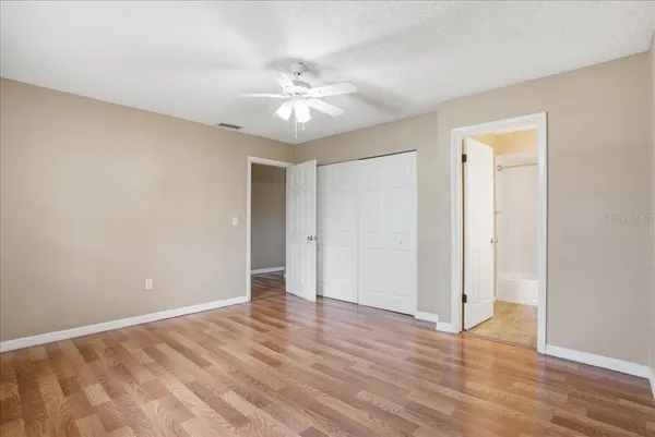 an empty room with wooden floor and fan