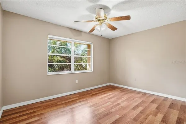 a view of empty room with wooden floor and fan