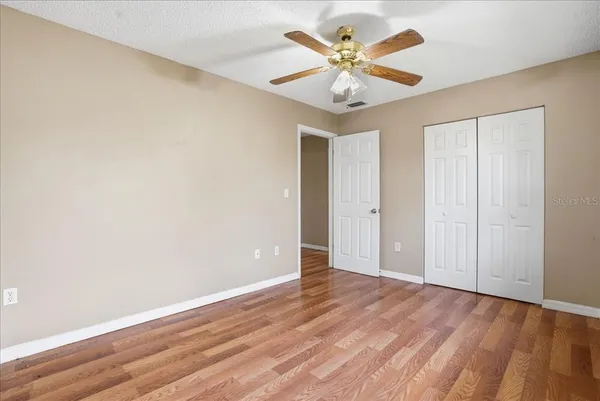 an empty room with wooden floor and a ceiling fan