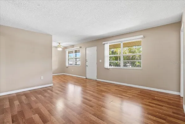 an empty room with wooden floor and windows