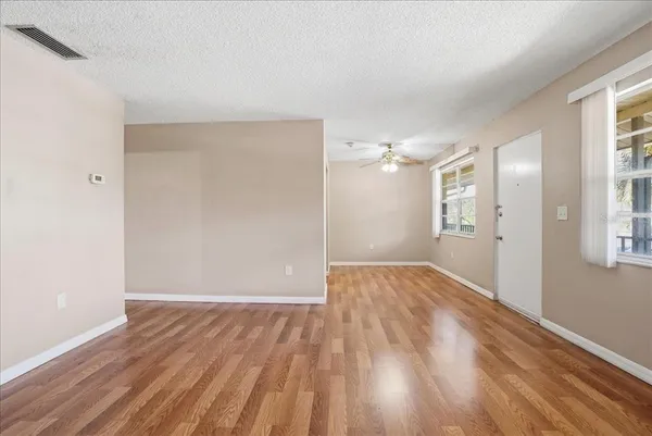a view of an empty room with wooden floor and a window