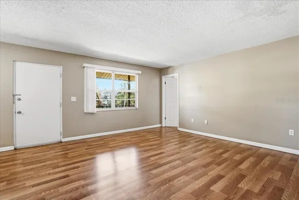a view of an empty room with wooden floor and a window