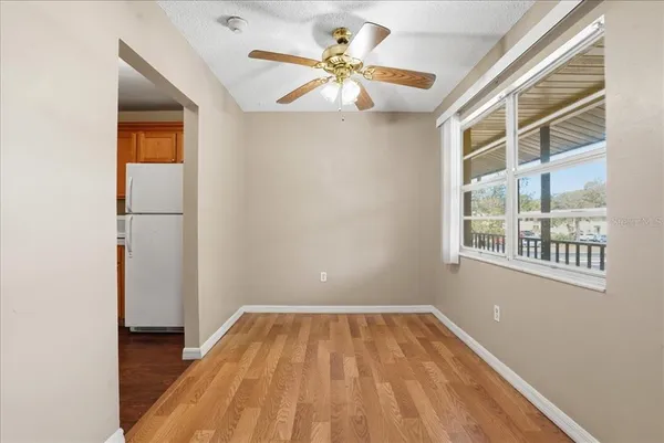 a view of empty room with wooden floor and fan