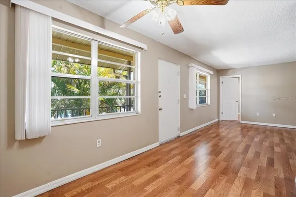 a view of an empty room with wooden floor and a window