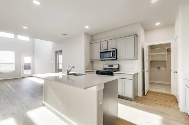 a kitchen with stainless steel appliances granite countertop a sink a stove and a refrigerator