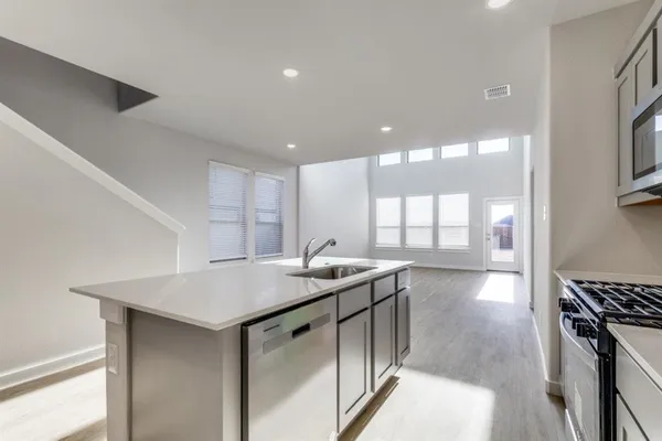 a kitchen with stainless steel appliances granite countertop a sink a stove and a wooden floors