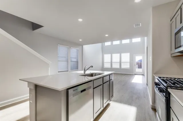 a kitchen with stainless steel appliances granite countertop a sink a stove and a wooden floors