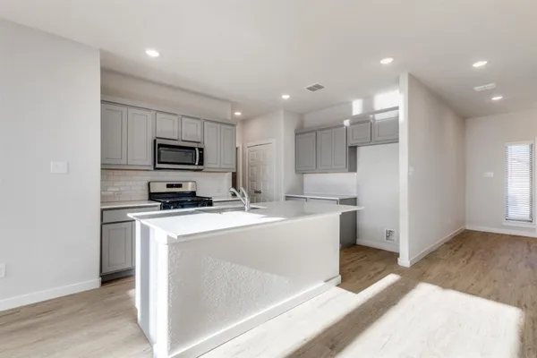 a open kitchen with white cabinets and stainless steel appliances
