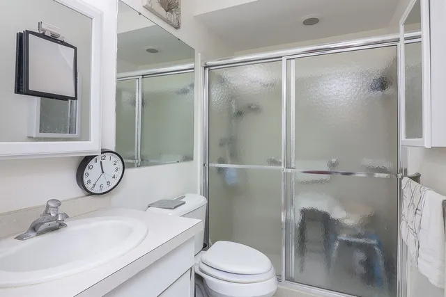 a bathroom with a shower sink vanity mirror and toilet