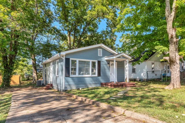 a front view of a house with a yard and trees