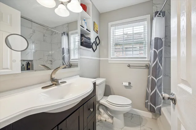 a bathroom with a sink a toilet a mirror and a window