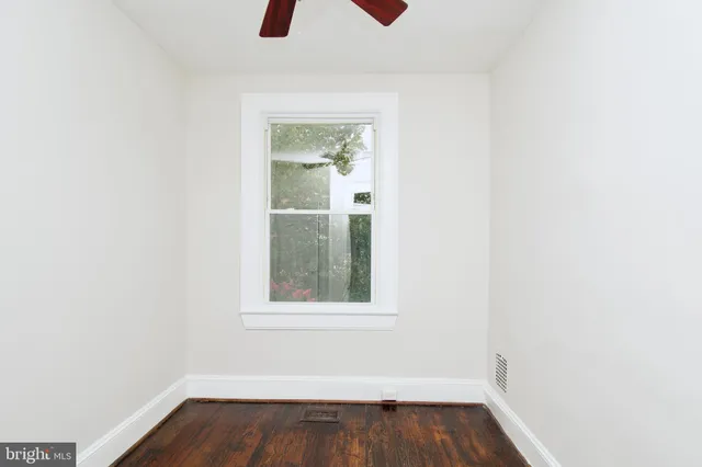 an empty room with wooden floor chandelier fan and windows