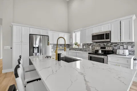 a kitchen with stainless steel appliances a stove a sink dishwasher a refrigerator and a stove with wooden floor